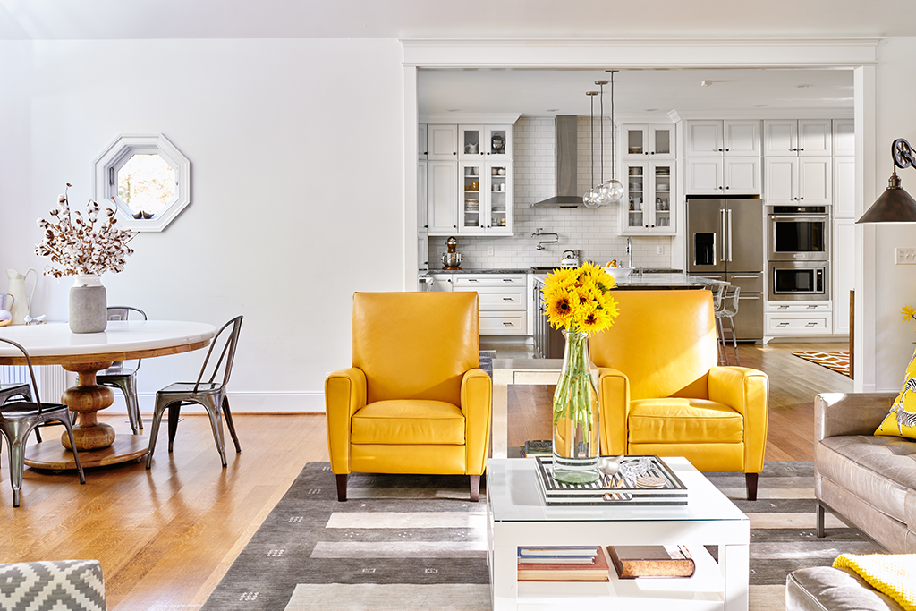 Pops of mustard yellow with leather recliners frame large cased opening to the kitchen