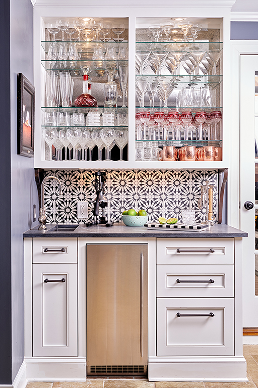Custom cabinetry, antique mirror and black and white floral tile bring bar to life