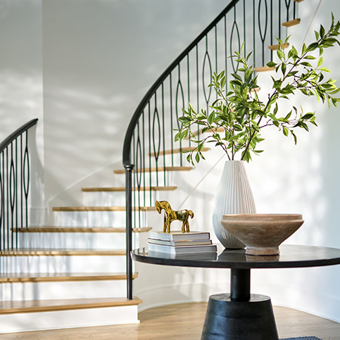 modern curving staircase with round entry table